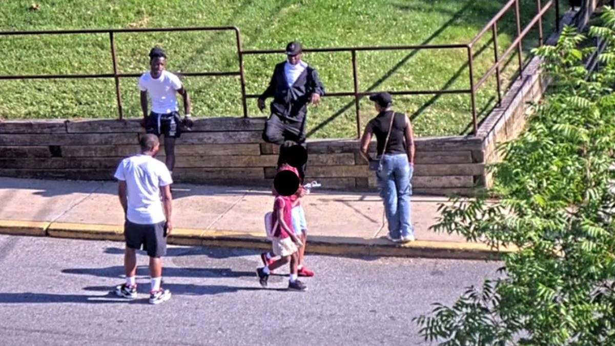 Surveillance image of people on a street corner.