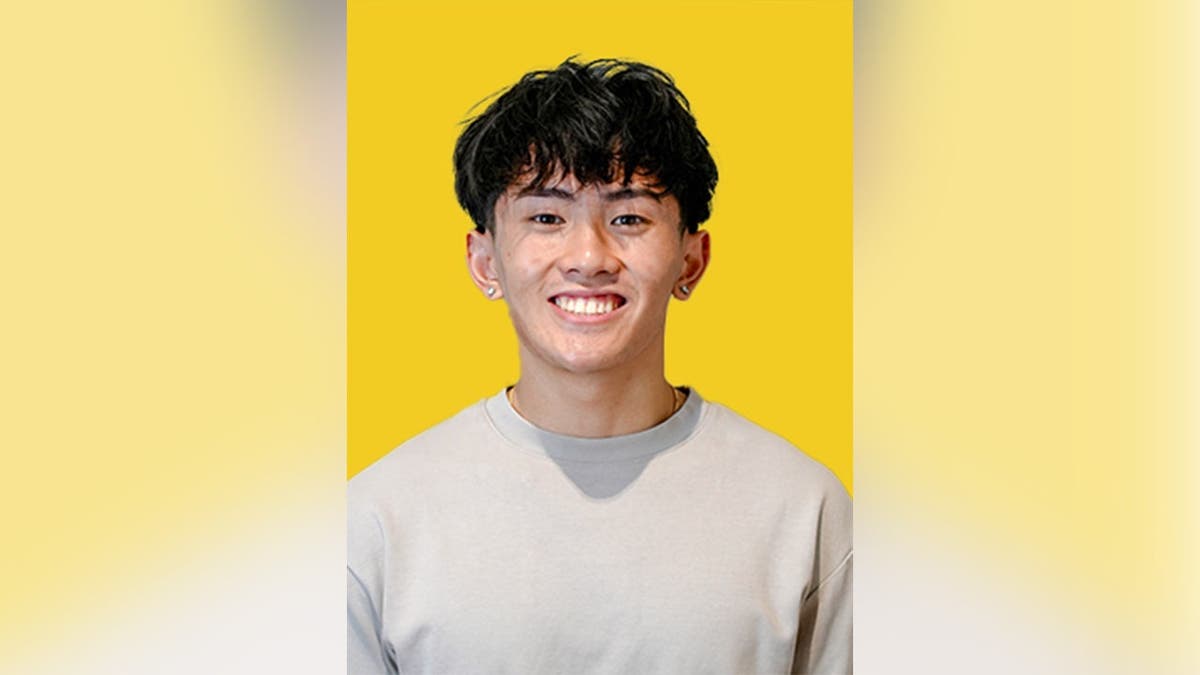 Kenny Truong smiling in front of a yellow background.