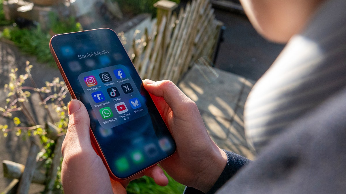 Person holding a phone displaying Meta social media screen.