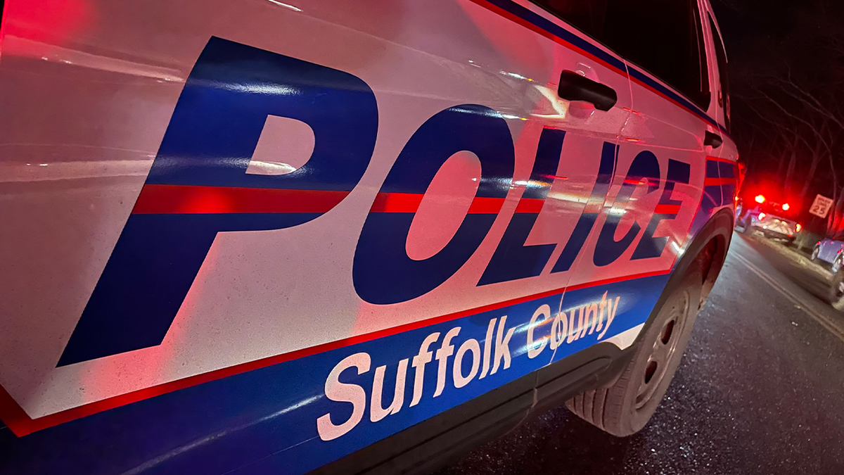 A Suffolk County Police vehicle with red lights flashing at night.