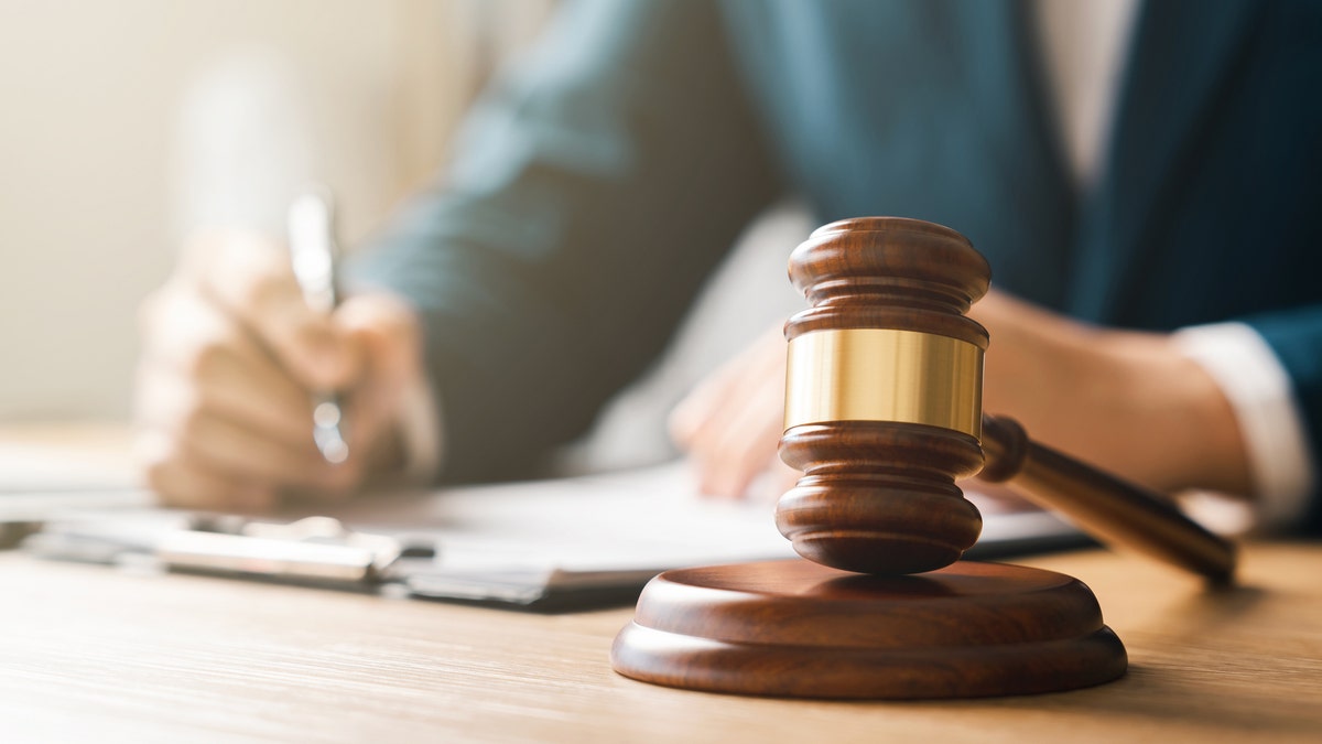 Man with pen and gavel in front.