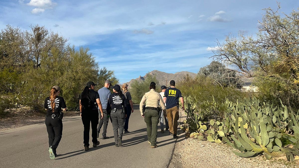 Law enforcement walking through a residential neighborhood in search of Nancy Guthrie