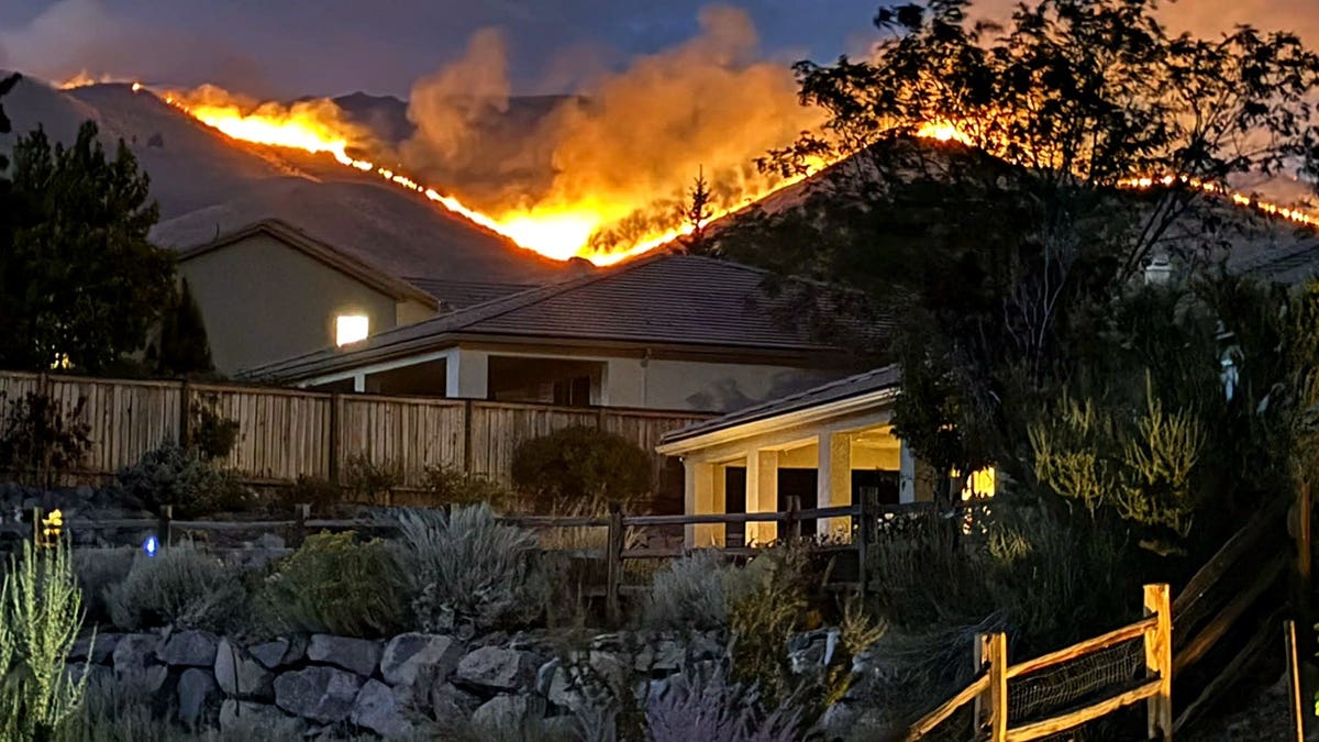 Flames burning in hills above a home