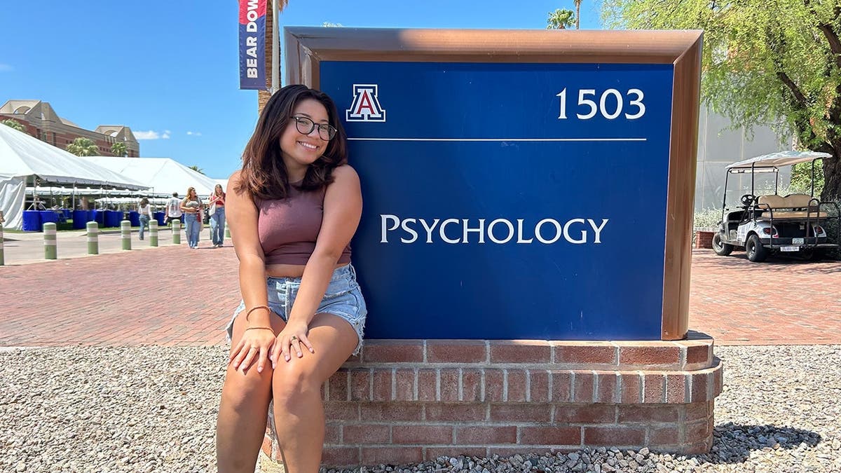 image shows Julie standing near UA psychology sign