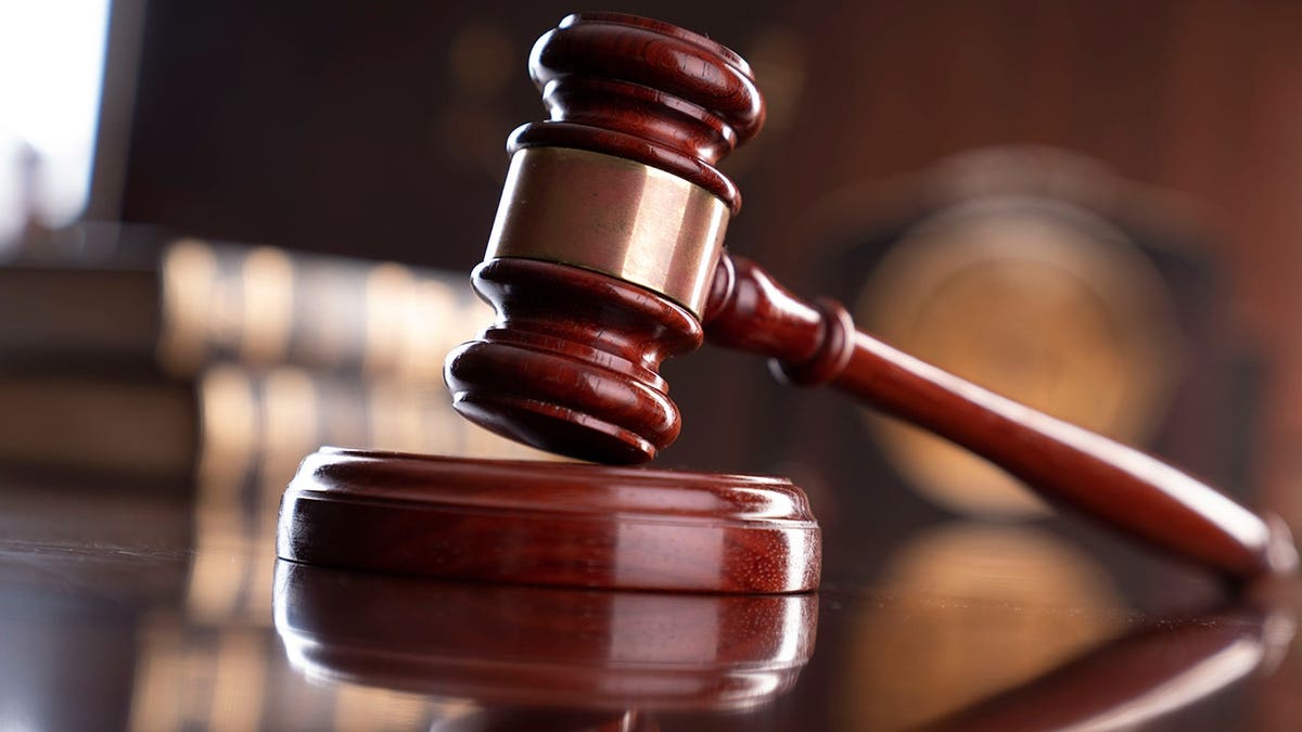 A gavel, legal books, and a statue of Themis on a judge's desk.