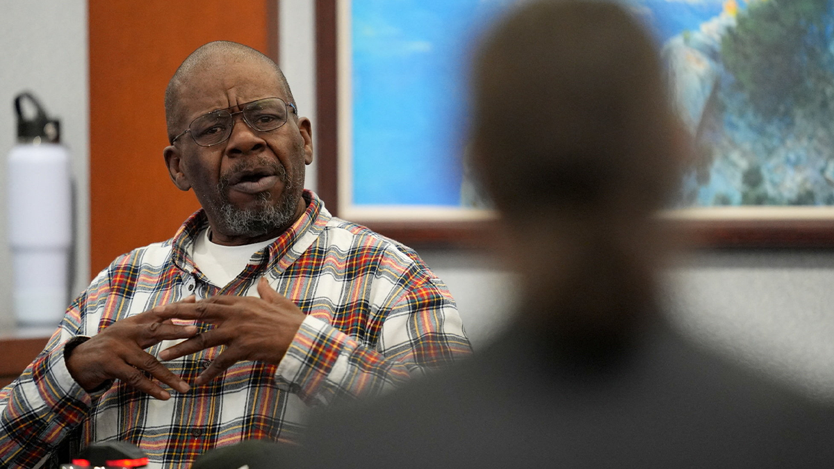 James McDonald is wearing a plaid shirt while answering questions on the witness stand