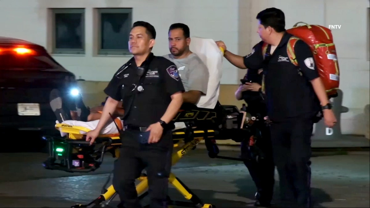 A man is transported on a stretcher by two officials.