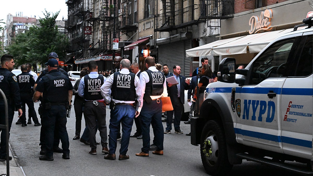 NYPD officers work at the scene where a suspect carrying a butcher knife was shot