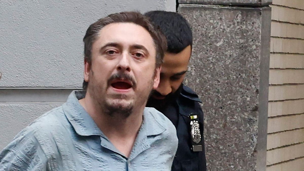 Andrew Truelove stands near security personnel at Rockefeller Center.