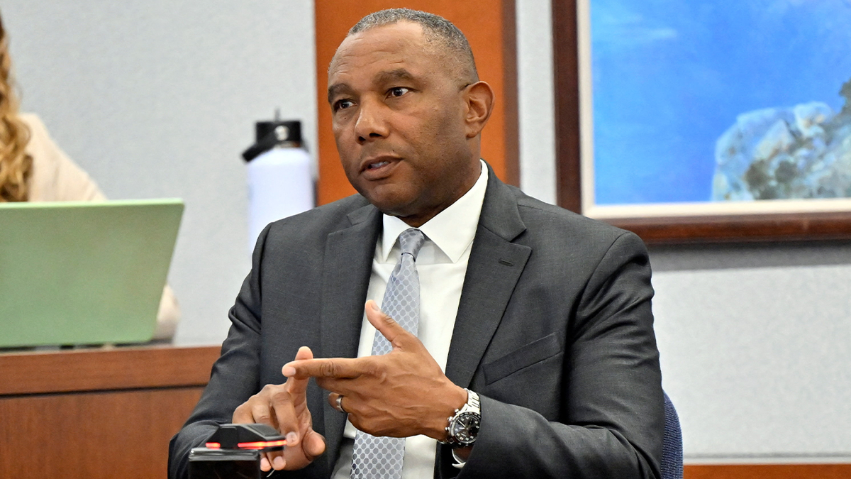 Former FBI special agent Wade Lee gestures while on the witness stand, wearing a dark suit and light tie