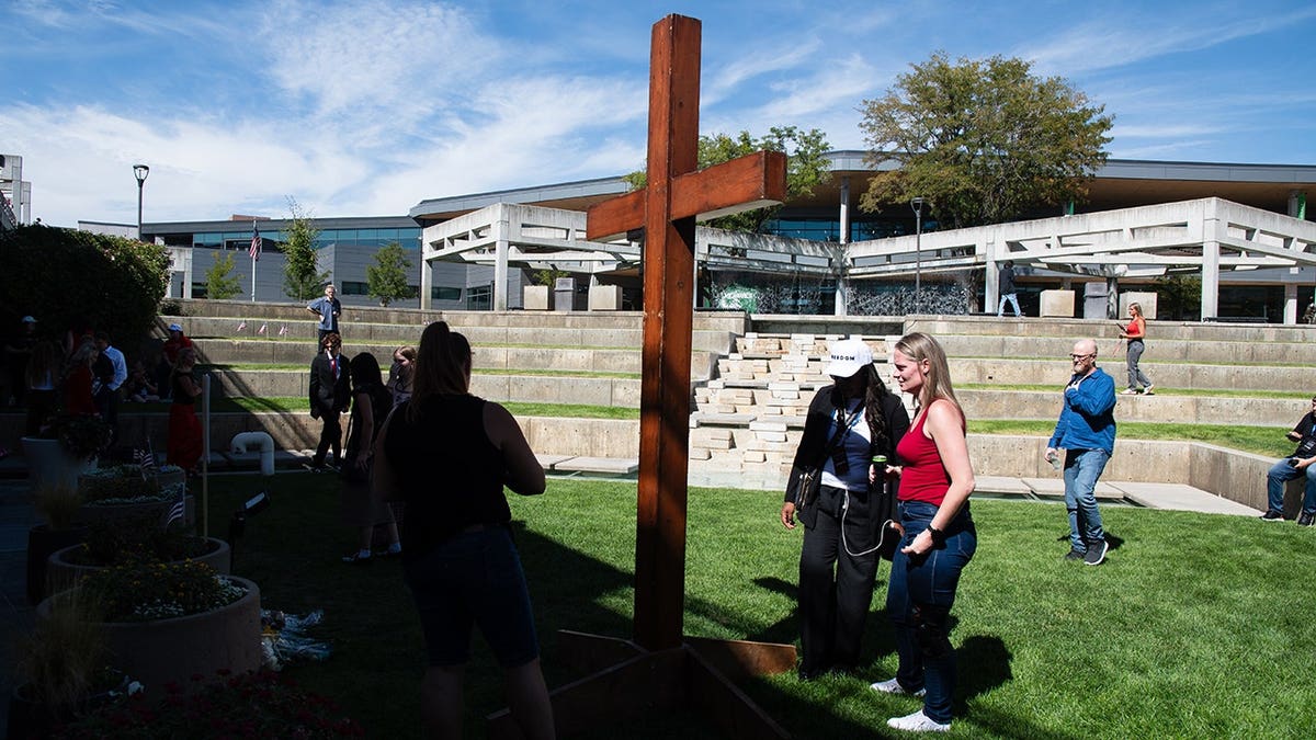 People gather around a large wooden cross at Utah Valley University in Orem, Utah.