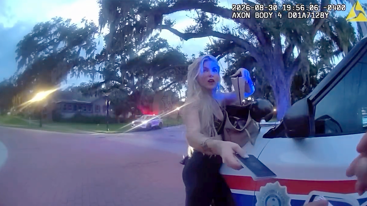 Elizabeth Boucher speaks with a Daytona Beach police officer beside a damaged vehicle