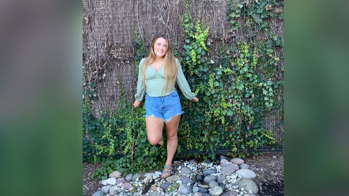 image shows Hannah standing against a wall