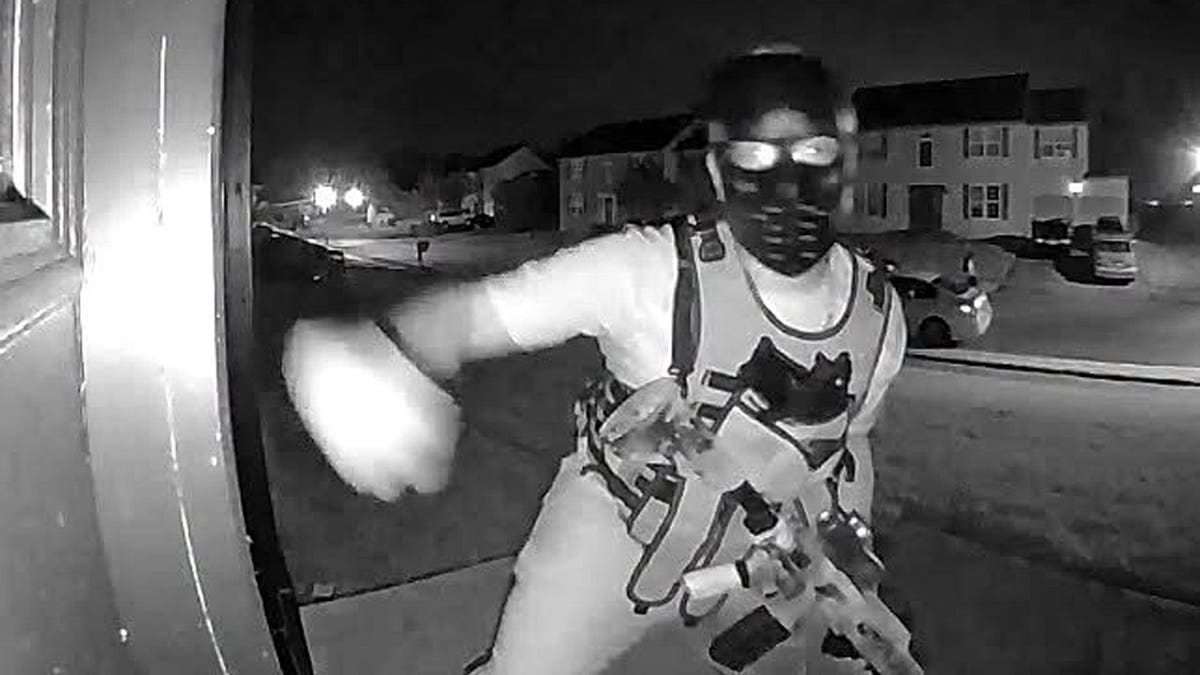 A masked individual wearing a tactical-style vest and carrying what appeared to be a rifle