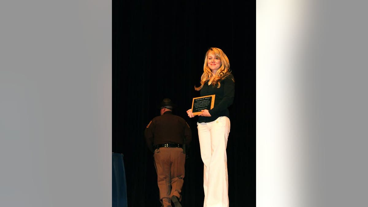 Kara Robinson Chamberlain holding an award.