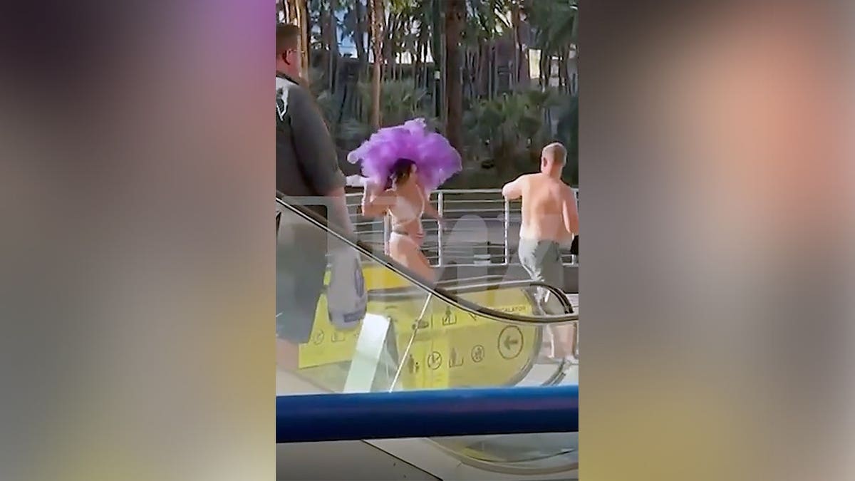 A woman wearing purple feathers and a white showgirl costume appears to grab another woman's hair during a fight on the Las Vegas Strip.