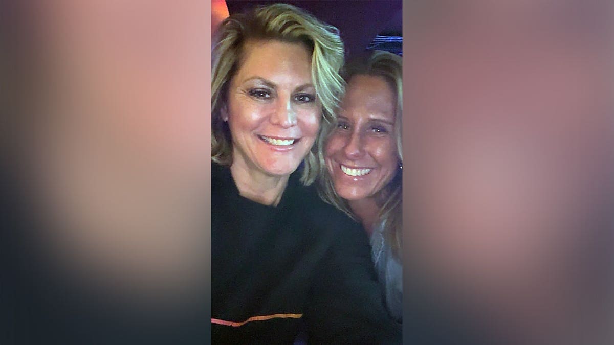 Misty Leslie, wearing a dark top, smiles beside another woman as the two pose for a close-up photograph.