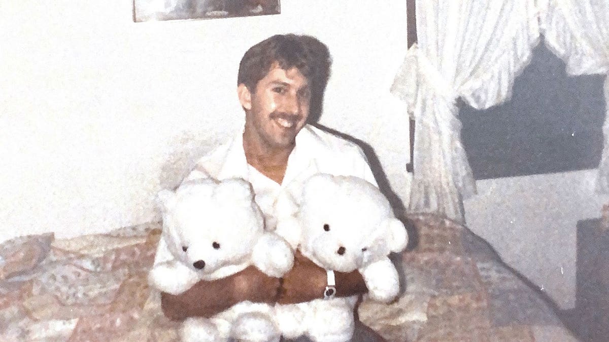 Richard Evonitz wearing white and holding two teddy bears.