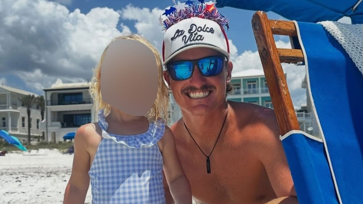Stone Romberg pictured with his young daughter on the beach.