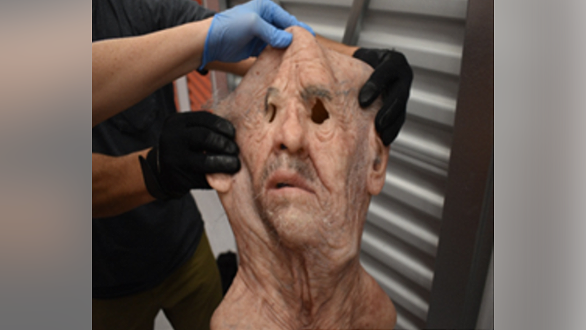 Gloved hands hold an old man mask with gray facial hair recovered in the David Sartin Jr. investigation