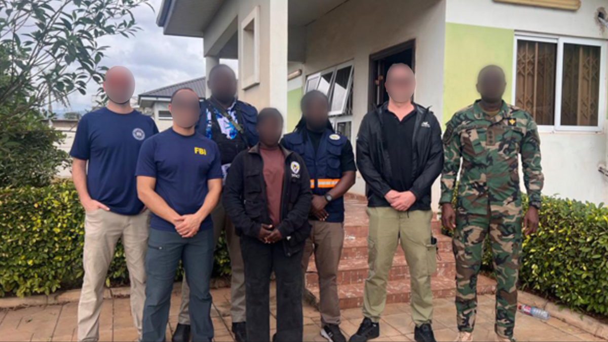 FBI personnel and other individuals posing outside a building during a scam center operation in Ghana