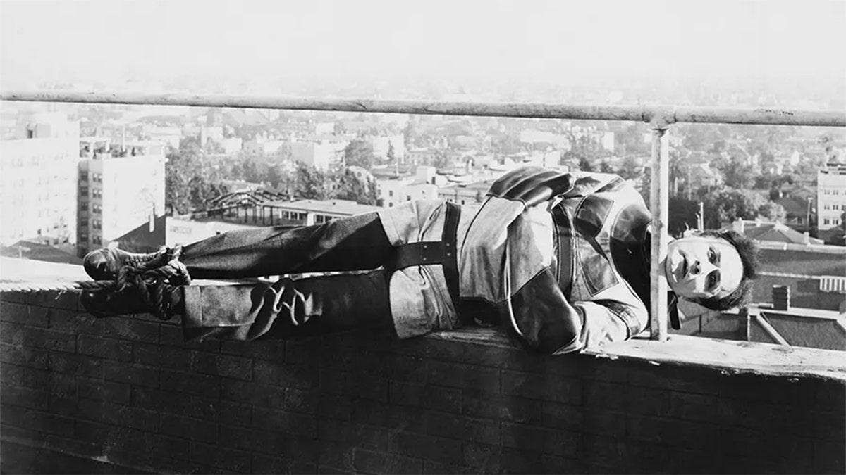 Harry Houdini holds onto railing