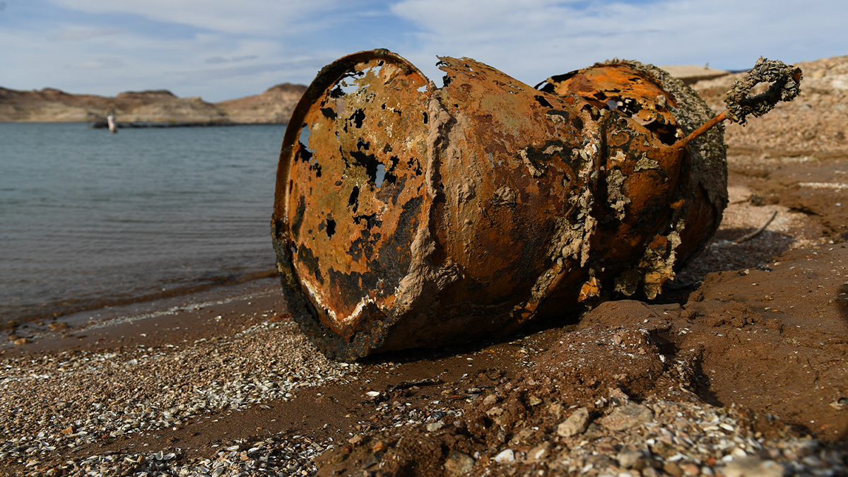 A rusted metal barrel on the shoreline of Lake Mead