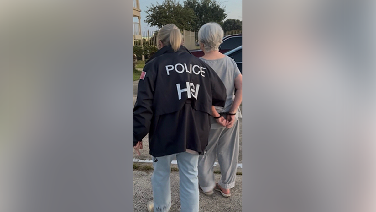 HSI agent escorts Lisa White with her hands cuffed behind her back in Long Beach, Mississippi
