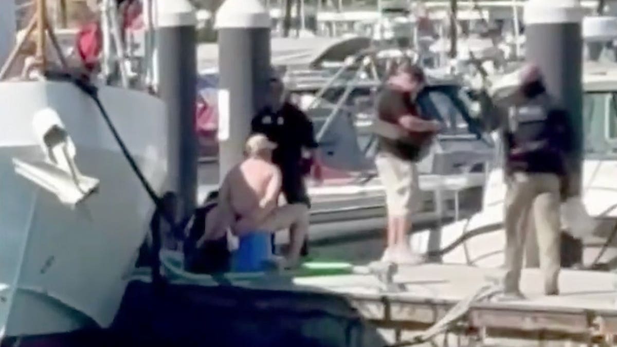Federal authorities stand near an intercepted vessel at a dock in Newport Beach, California.