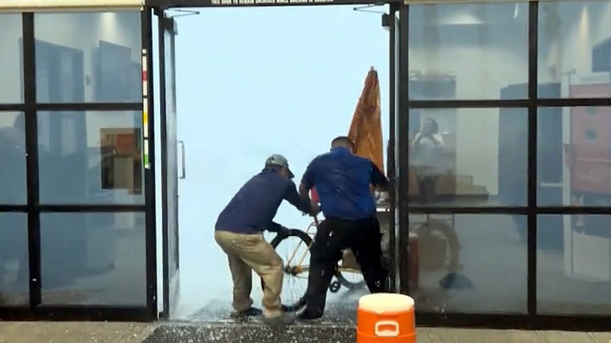 PNC Bank employees help a local food vendor pull his cart inside as powerful winds and hail sweep through Phoenix, Arizona.