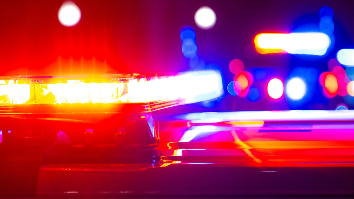 Close-up of flashing red, blue and yellow emergency lights on police vehicles at night.