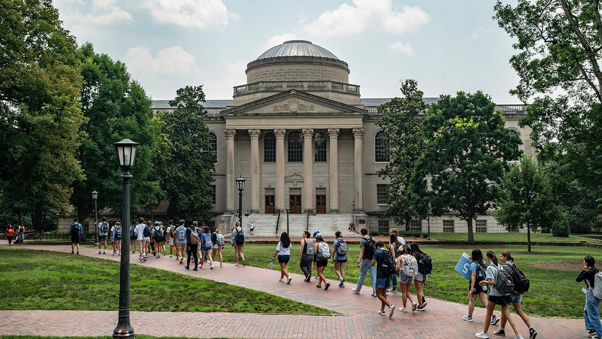 A line of students walk on the campus of the University of North Carolina