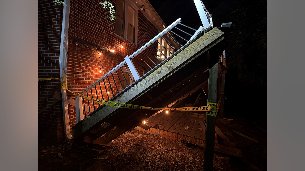Collapsed wooden porch and broken railing behind police tape at a brick home in Williamsburg, Virginia